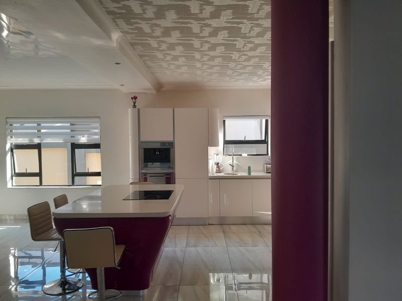 Modern kitchen featuring a central island with integrated cooktop, sleek cabinetry, built-in appliances, and polished tiled flooring.