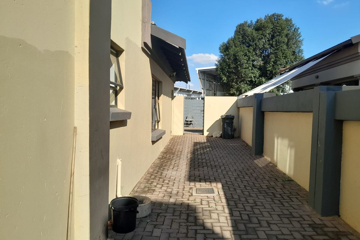 A side exterior walkway featuring paved flooring and boundary walls, providing access along the side of the property.