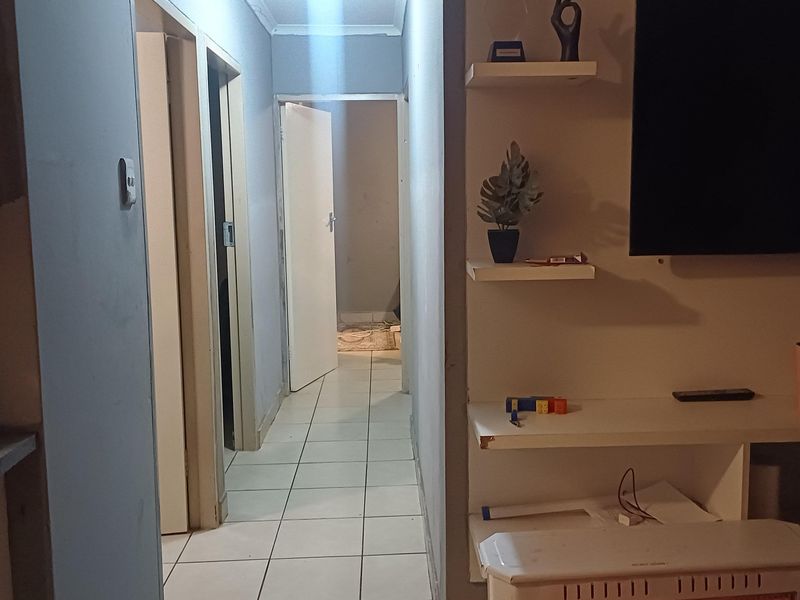 A functional hallway featuring tiled flooring and built-in shelving, providing access to adjacent rooms within the home.