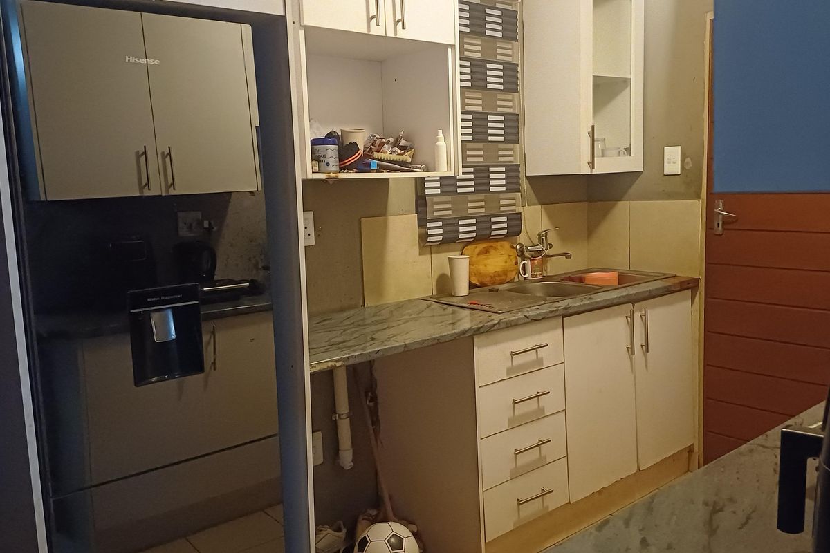 A compact kitchen featuring built-in cabinetry, laminate countertops, and a stainless steel sink, requiring some cosmetic updates to improve functionality and aesthetic appeal.