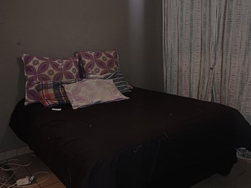 A bedroom featuring tiled flooring and wall-mounted curtain tracks, currently requiring cosmetic updates to improve the overall finish and lighting.