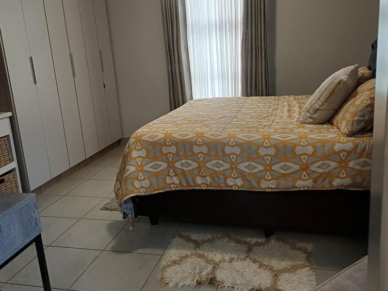 A well-maintained bedroom featuring neutral tiled flooring and extensive built-in cupboard storage.