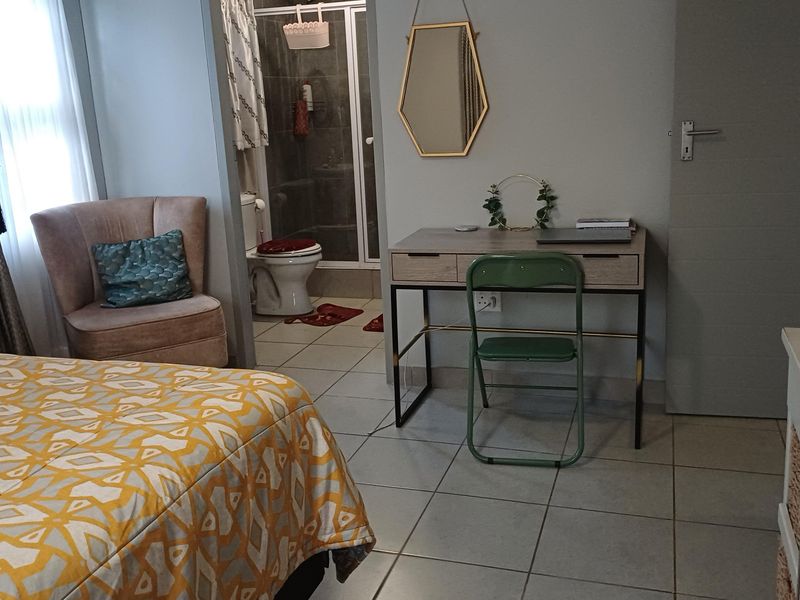 A bedroom featuring tiled flooring and an attached en-suite bathroom with a shower enclosure.