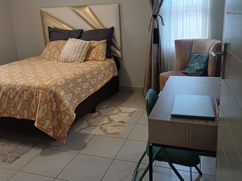 A functional bedroom featuring tiled flooring and neutral wall finishes, providing a comfortable and practical living space.