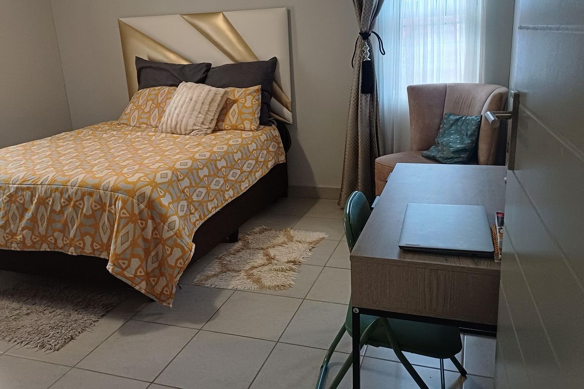 A functional bedroom featuring tiled flooring and neutral wall finishes, providing a comfortable and practical living space.