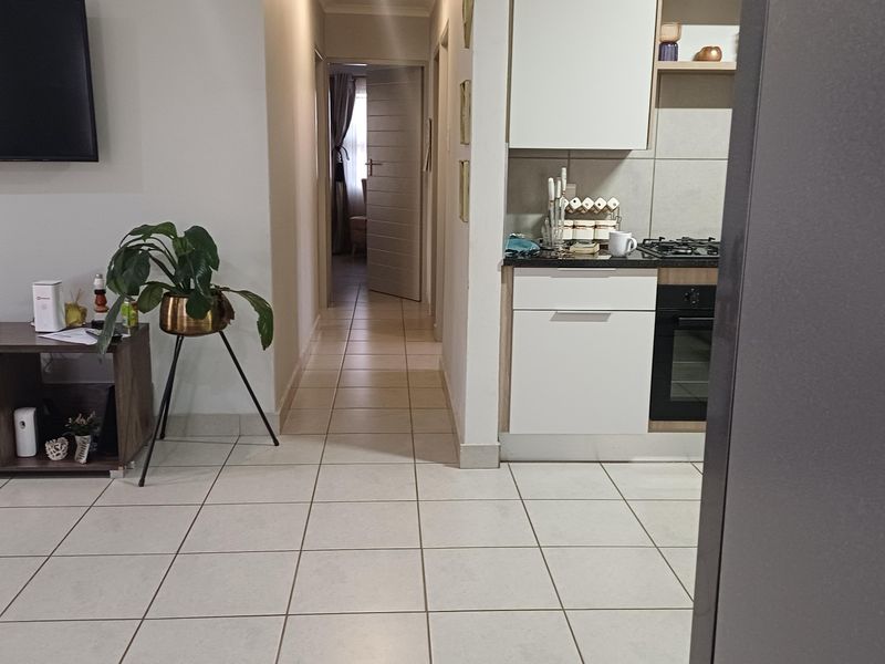 Open plan living area featuring tiled flooring, leading into a modern kitchen with built-in cabinetry, oven, and gas hob.