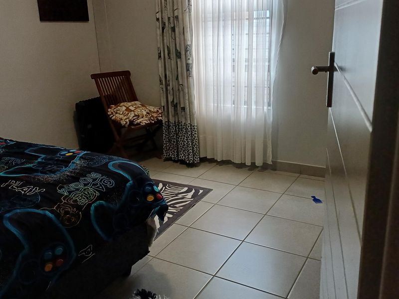 A bedroom featuring tiled flooring and a window with curtain tracks, offering a functional space with neutral finishes.