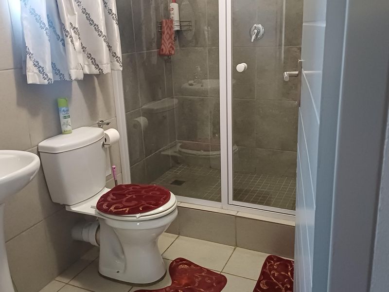 A functional bathroom featuring a pedestal basin, a standard toilet, and a tiled shower enclosure with a glass door.
