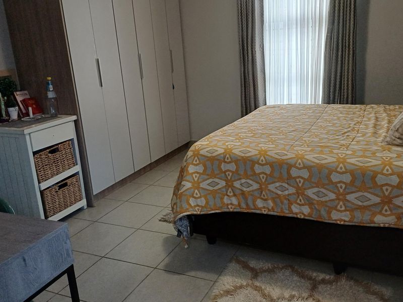 A well-maintained bedroom featuring neutral tiled flooring and ample built-in cupboard storage space.