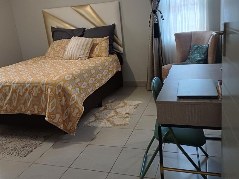 A bedroom featuring tiled flooring and neutral wall finishes, providing a functional space for rest and study.