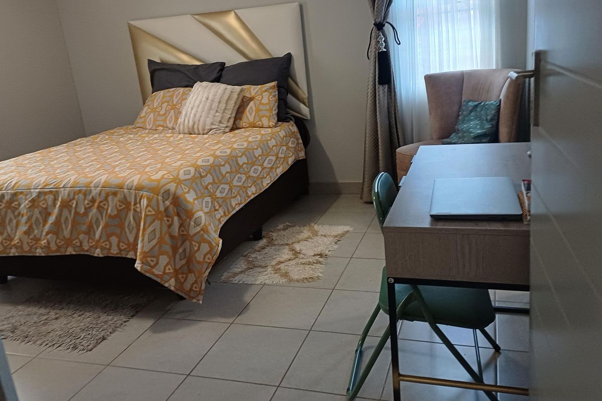 A bedroom featuring tiled flooring and neutral wall finishes, providing a functional space for rest and study.