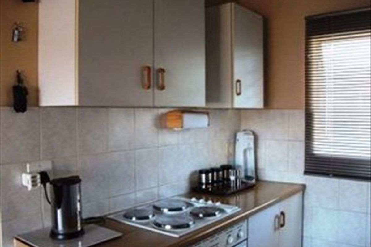 A functional kitchen area featuring built-in cabinetry, an electric hob, an integrated oven, and tiled backsplash finishes.