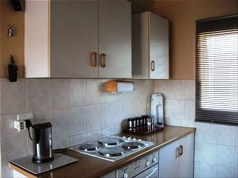 A functional kitchen area featuring built-in cabinetry, an electric hob, an integrated oven, and tiled backsplash finishes.