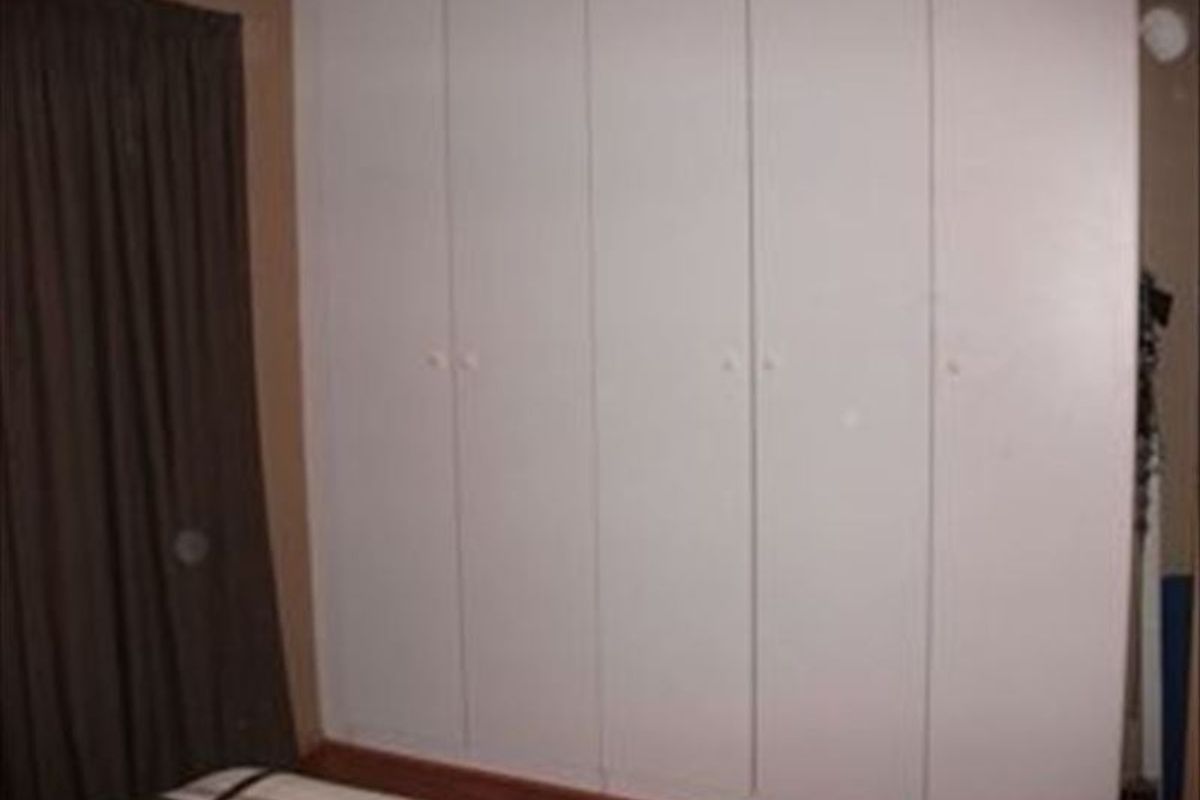 A bedroom featuring floor-to-ceiling built-in cupboards with white doors.