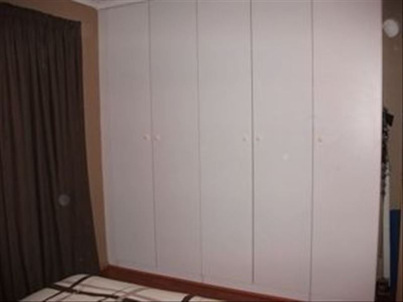 A bedroom featuring floor-to-ceiling built-in cupboards with white doors.