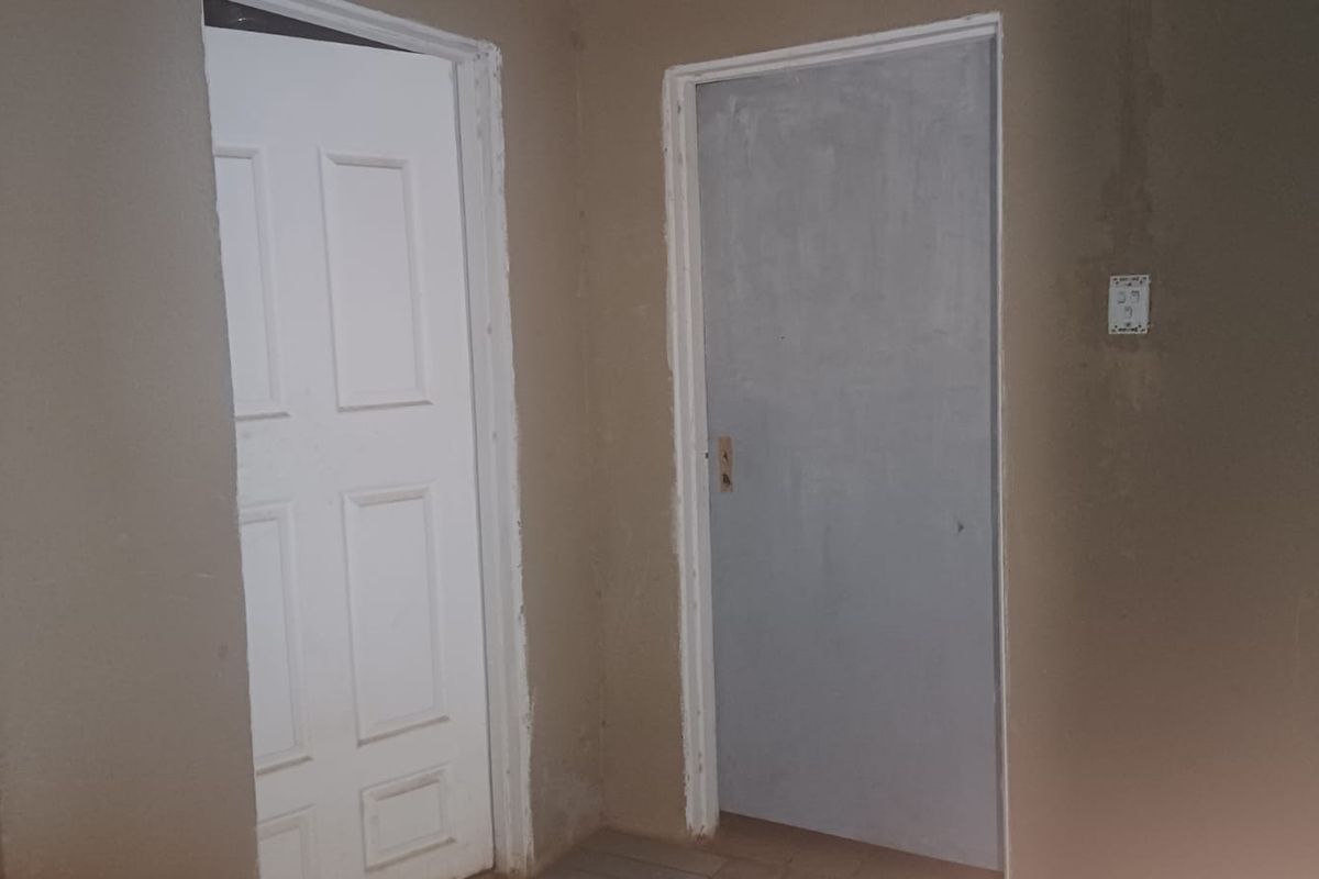 A hallway area featuring two interior doors and unfinished wall surfaces, requiring cosmetic attention and finishing touches.