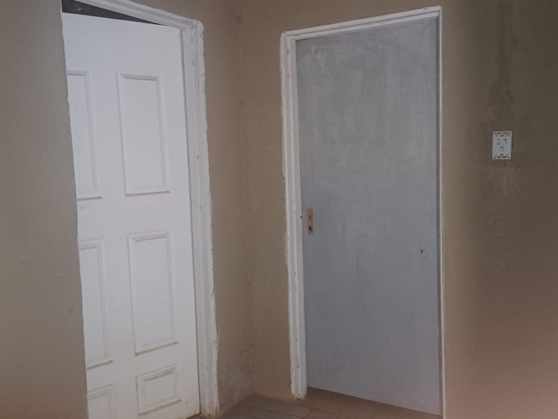 A hallway area featuring two interior doors and unfinished wall surfaces, requiring cosmetic attention and finishing touches.