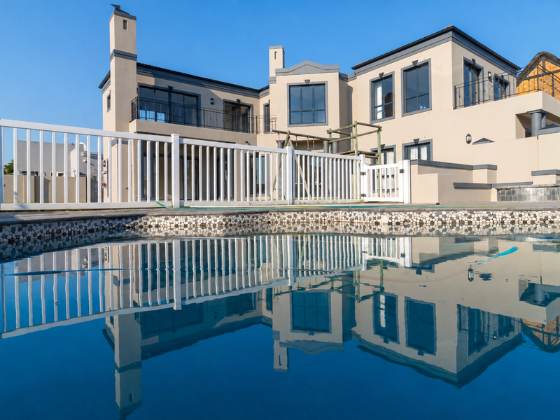 A clear view of the rear exterior of the house featuring a swimming pool with a white fence and modern architectural details.