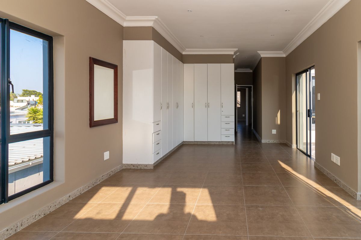 Spacious bedroom featuring neutral walls, extensive built-in cabinetry, tiled flooring, and large sliding doors providing ample natural light.