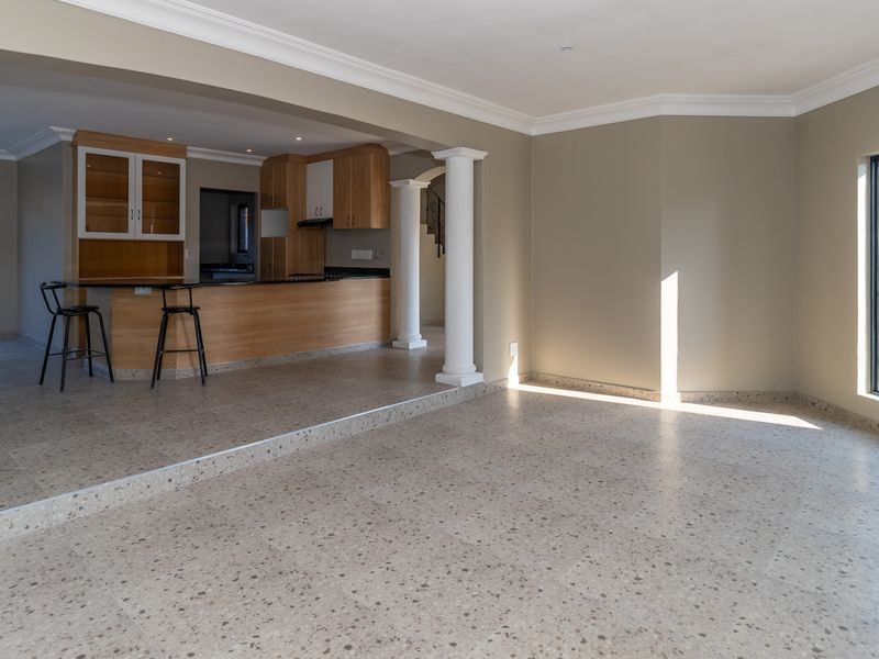Spacious open-plan living and kitchen area featuring terrazzo flooring, built-in cabinetry, and a kitchen island, offering a bright and versatile layout.