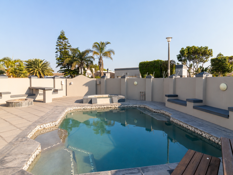 Outdoor entertainment area featuring a swimming pool, built-in seating, and a fire pit, enclosed by a secure perimeter wall.