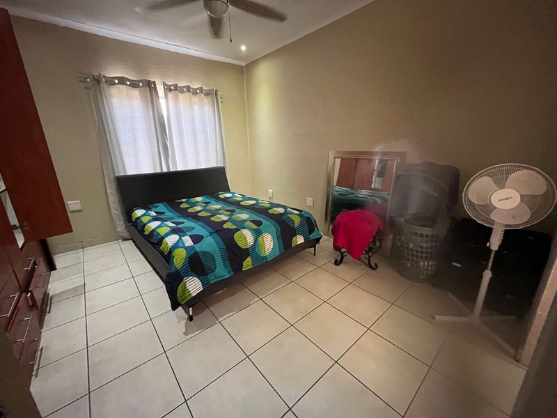 A functional bedroom featuring tiled flooring, a ceiling fan, and built-in cupboard storage, offering a neutral base for personalization.