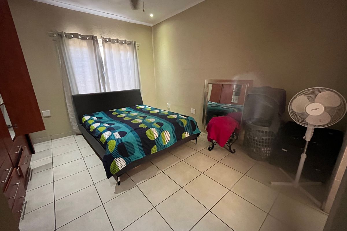 A functional bedroom featuring tiled flooring, a ceiling fan, and built-in cupboard storage, offering a neutral base for personalization.