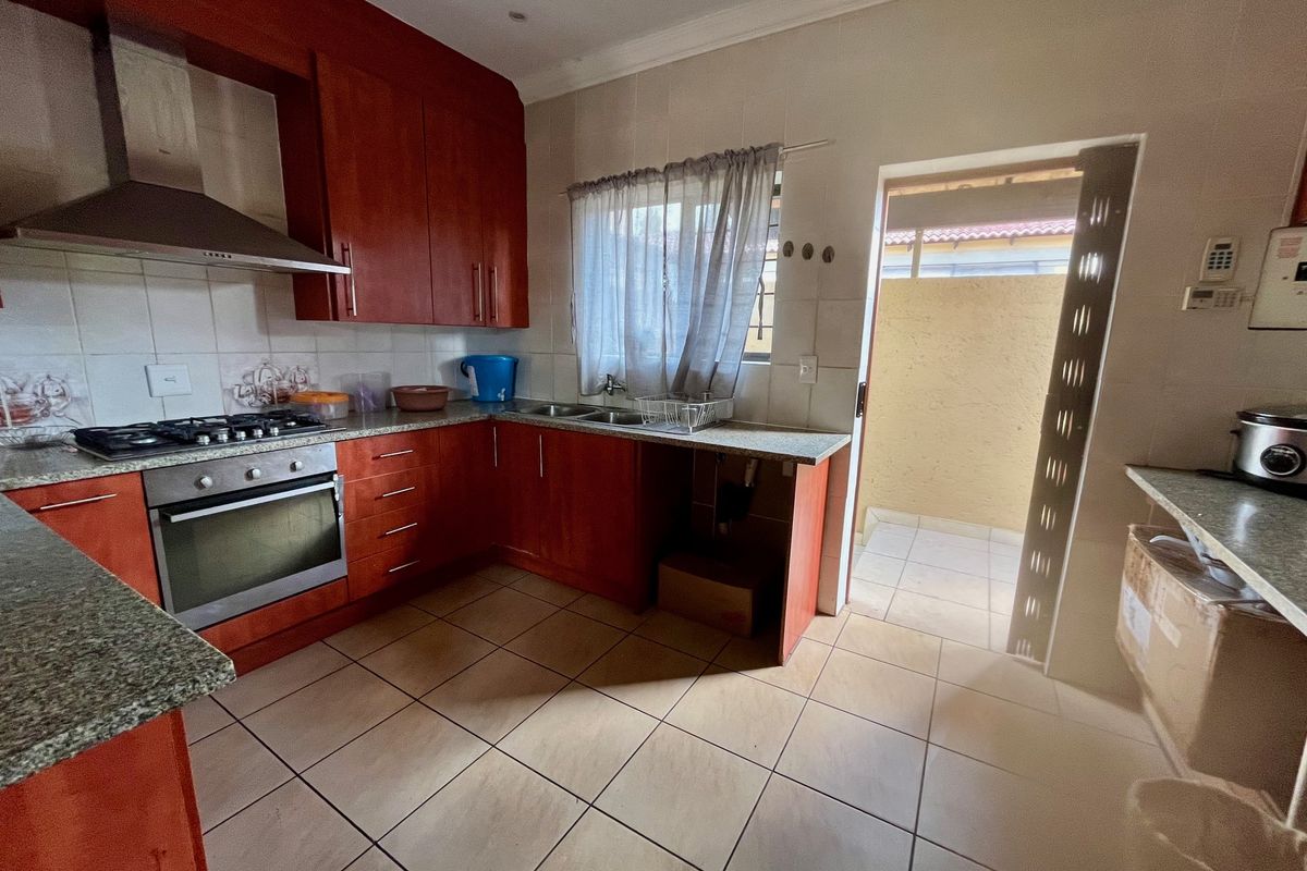 Functional kitchen featuring warm-toned cabinetry, granite countertops, built-in oven, gas hob, and direct access to an outdoor area.