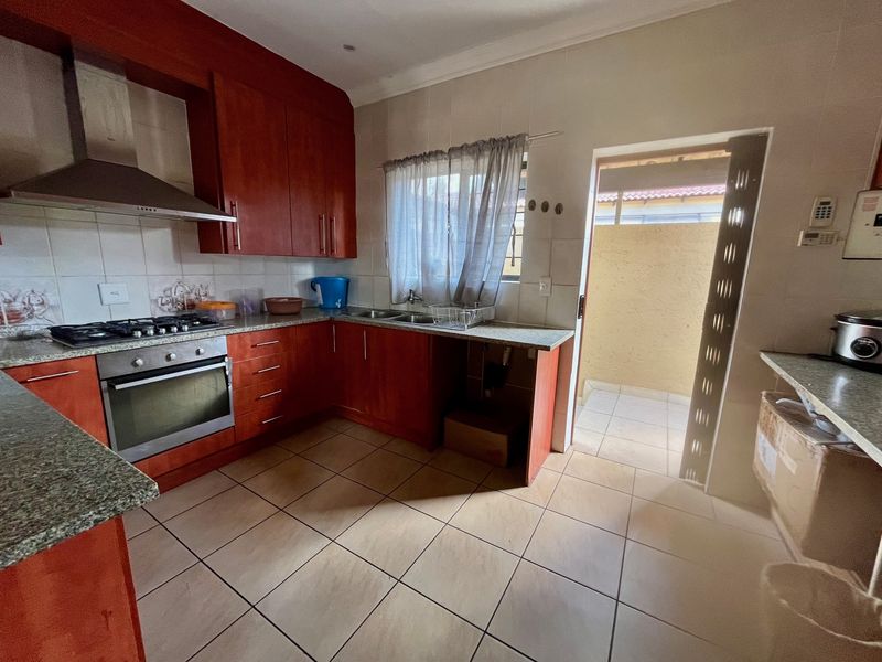 Functional kitchen featuring warm-toned cabinetry, granite countertops, built-in oven, gas hob, and direct access to an outdoor area.