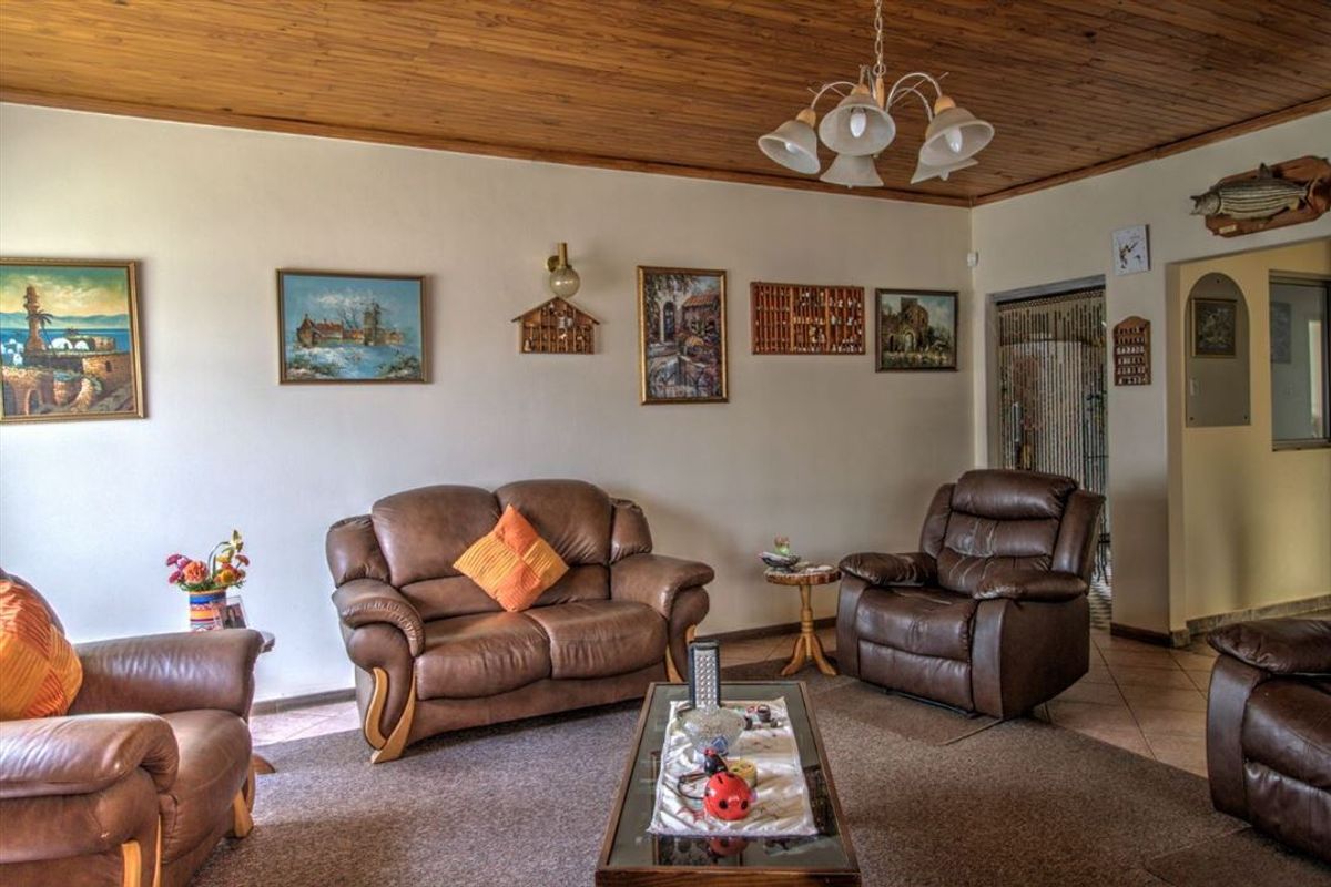 A living room featuring a timber-clad ceiling, tiled flooring, and a central ceiling light fixture.