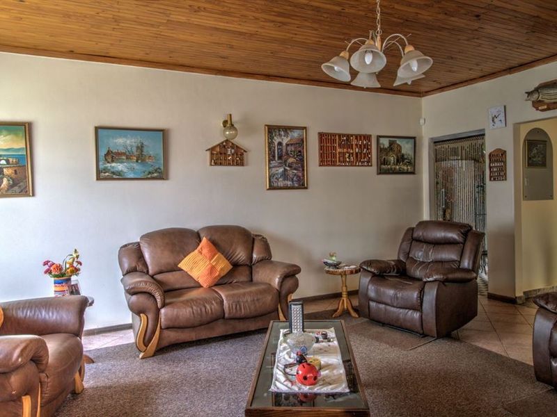 A living room featuring a timber-clad ceiling, tiled flooring, and a central ceiling light fixture.