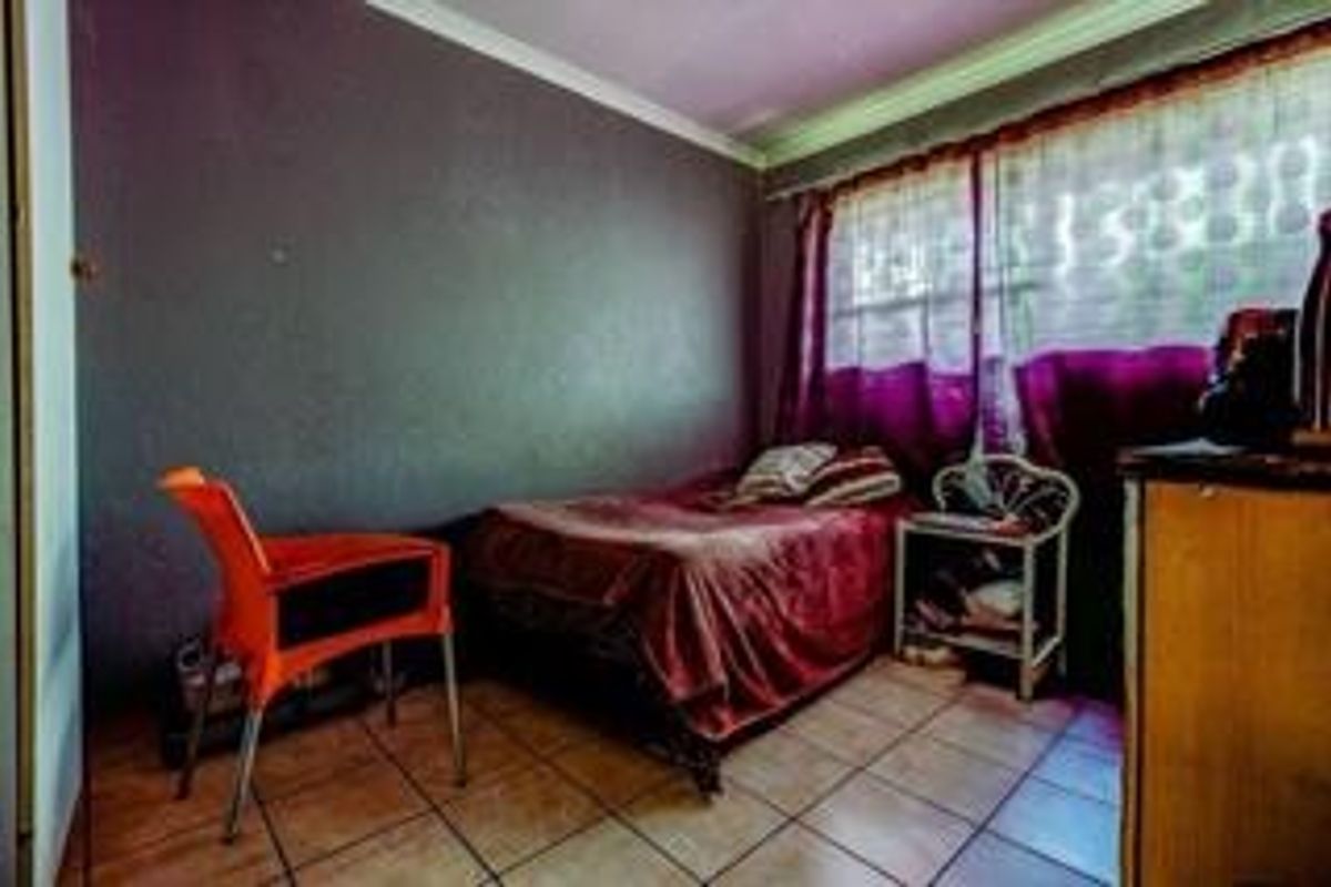 A bedroom featuring tiled flooring and coved ceilings, currently requiring cosmetic updates to the wall finishes.