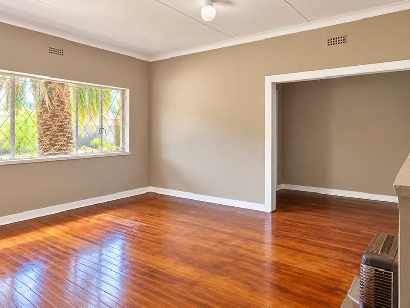 Spacious living room featuring polished hardwood flooring, large diamond pane windows, and a built-in fireplace, offering a bright and neutral canvas.
