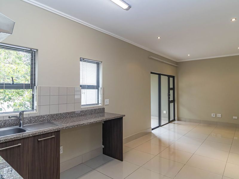 Modern open-plan kitchen and living area featuring tiled floors, granite countertops, and direct access to an outdoor space through a glass door.