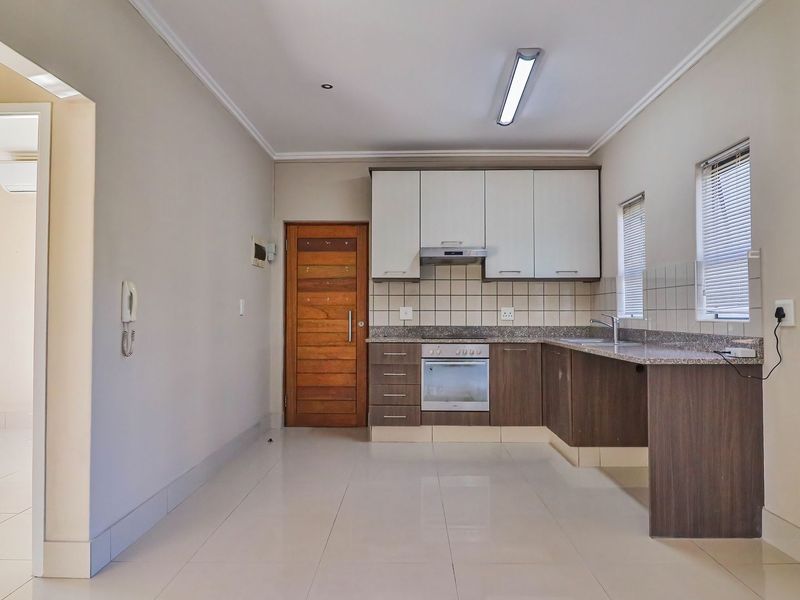 A clean, functional kitchen featuring modern cabinetry, granite countertops, built-in oven, extractor fan, and tiled flooring, offering a bright and well-maintained space.