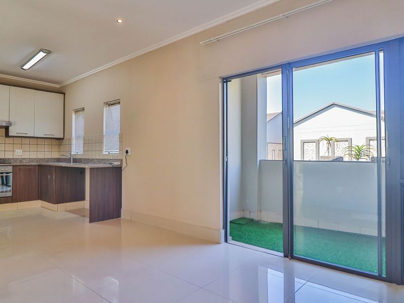 Open-plan kitchen and living area featuring modern cabinetry, granite countertops, built-in appliances, and large sliding doors leading to a private balcony.