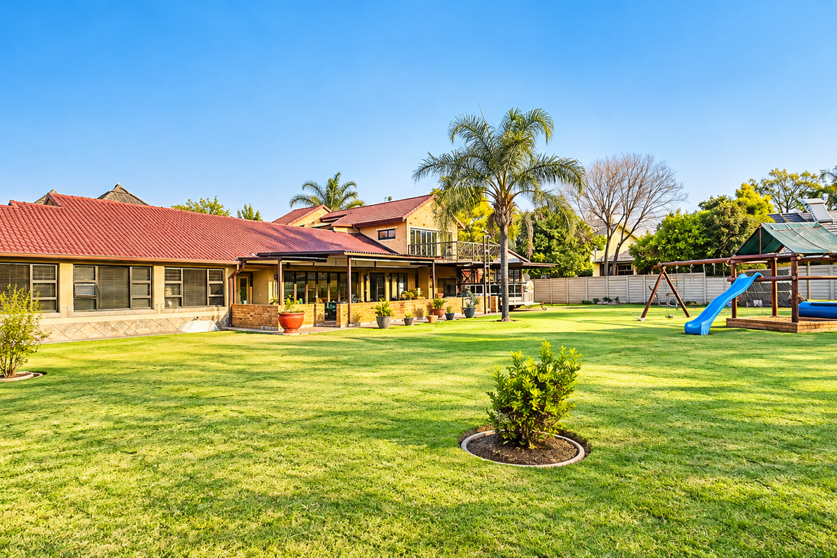 Spacious rear garden featuring a well-maintained lawn, covered patio area, and a multi-level house structure with a tiled roof.