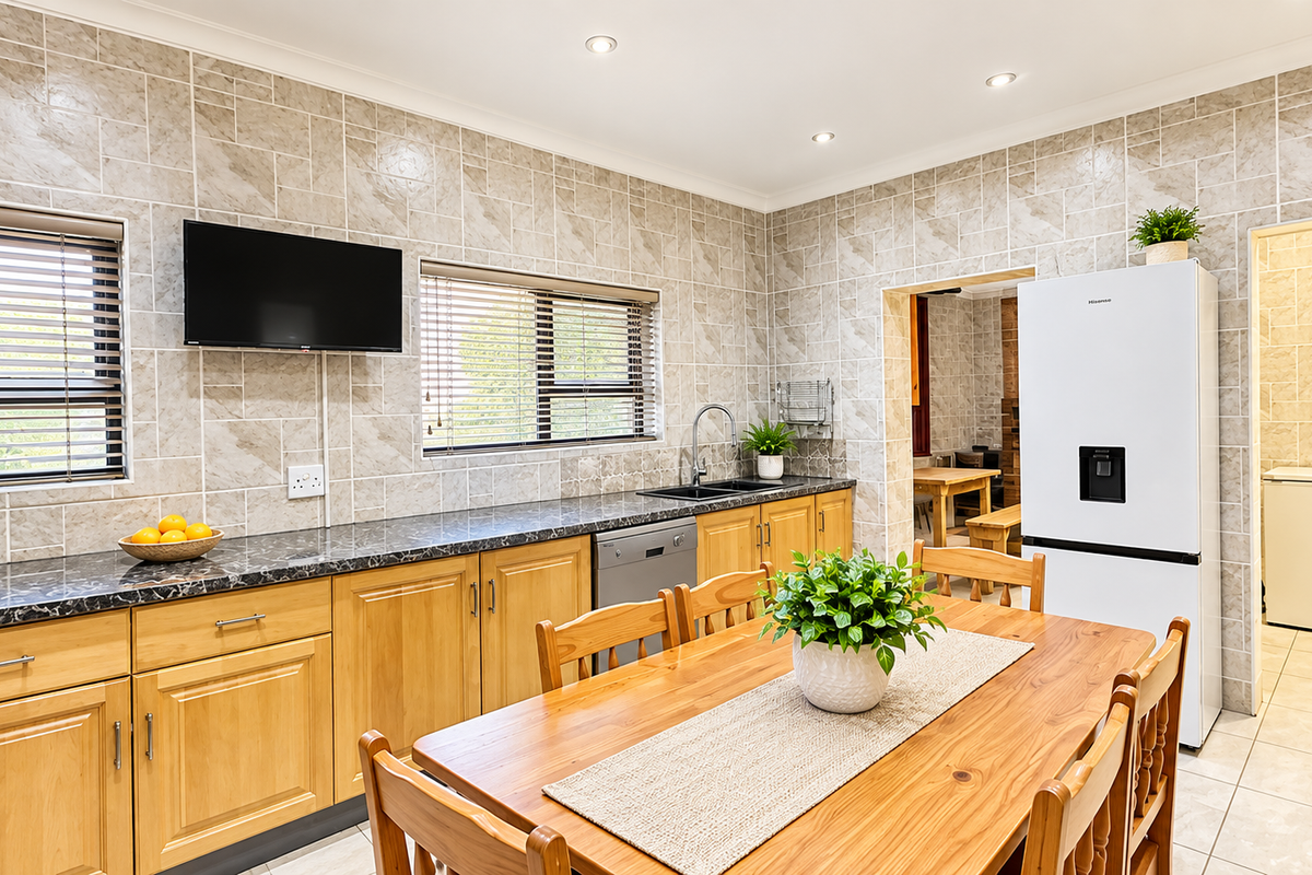 A functional kitchen featuring wooden cabinetry, laminate countertops, tiled splashbacks, and a double basin sink, with an adjacent scullery area.
