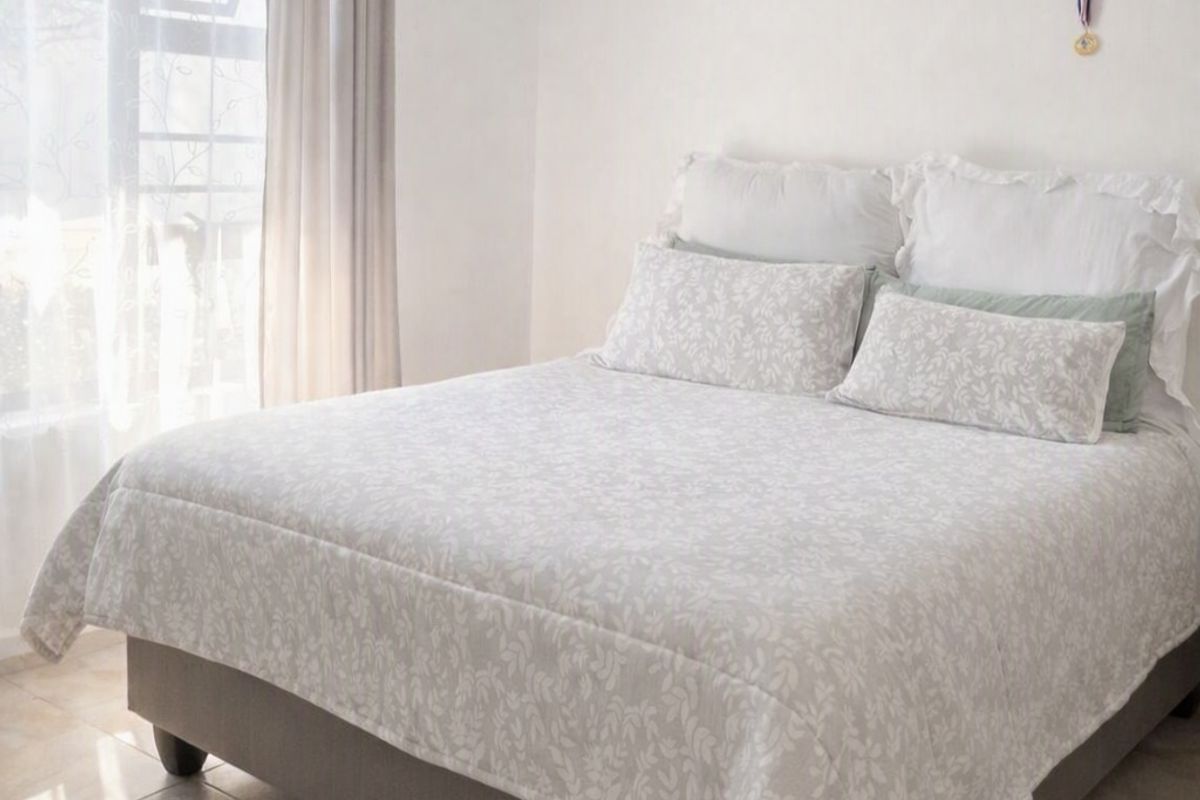 A bright bedroom featuring neutral tiled flooring and a large window allowing for ample natural light.
