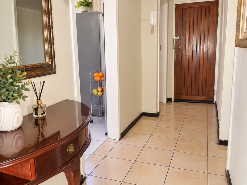 A welcoming entrance hall featuring neutral tiled flooring and a solid wood front door, providing a clean and functional transition into the home.