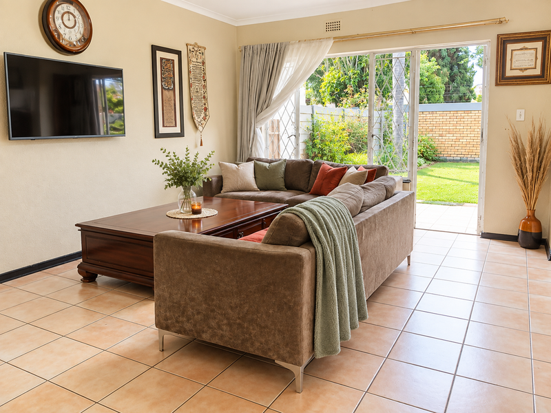 Spacious living room featuring ceramic floor tiles and a large sliding glass door providing direct access to the rear garden.