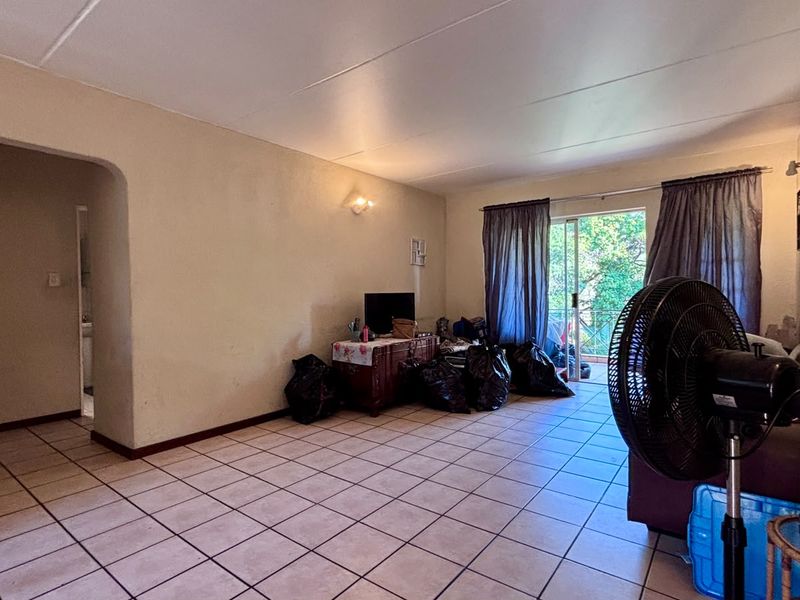Open-plan living area featuring ceramic floor tiles, an arched entryway, and a sliding glass door providing access to an outdoor space.
