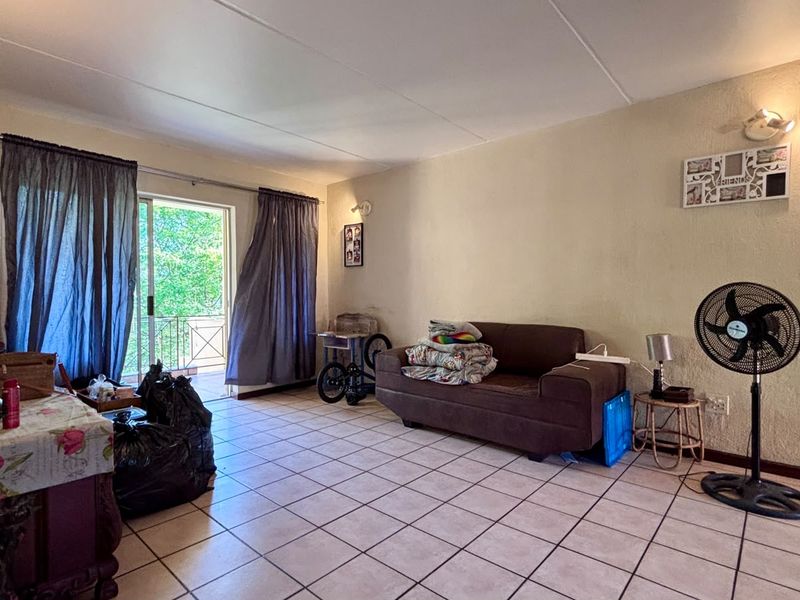A living room area featuring tiled flooring and a sliding glass door leading to an outdoor space, with neutral wall finishes.
