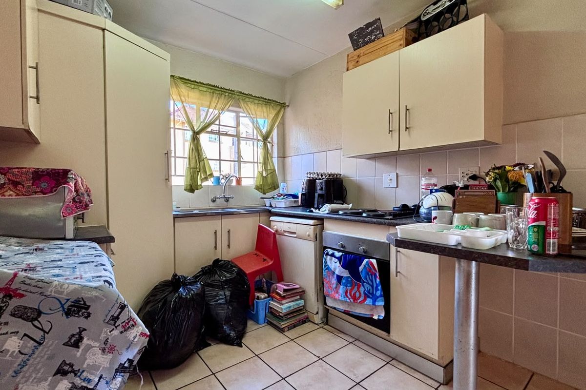 Compact kitchen featuring built-in cabinetry, laminate countertops, a built-in oven, and tiled flooring. The space offers functional storage and preparation areas.