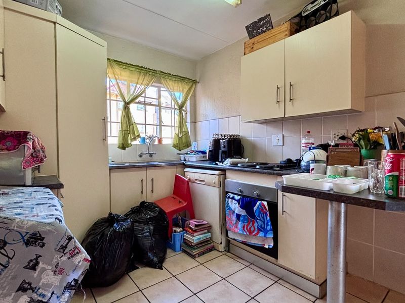 Compact kitchen featuring built-in cabinetry, laminate countertops, a built-in oven, and tiled flooring. The space offers functional storage and preparation areas.