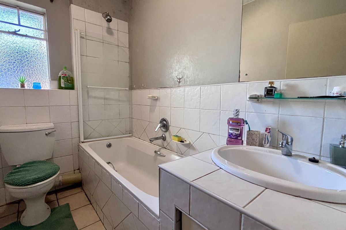 A functional bathroom featuring a tiled vanity with drop-in basin, a bathtub with shower attachment, and tiled wall finishes.
