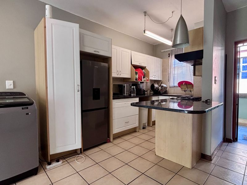 A functional kitchen featuring built-in cabinetry, granite countertops, a breakfast nook, and tiled flooring, with direct access to an outdoor balcony area.