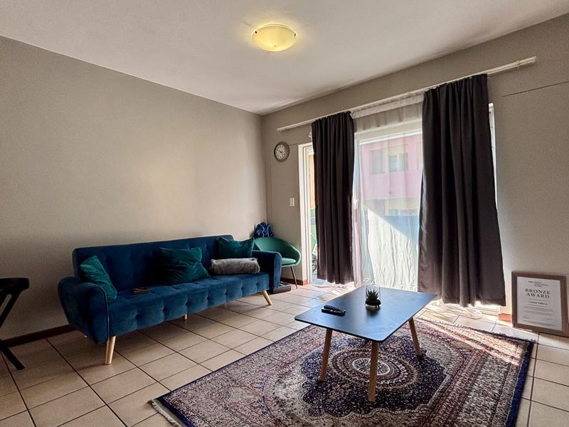 A living room featuring tiled flooring and a sliding glass door providing access to an outdoor area.