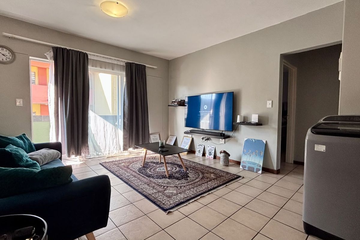 A living room featuring tiled flooring and a sliding glass door providing access to an outdoor area.