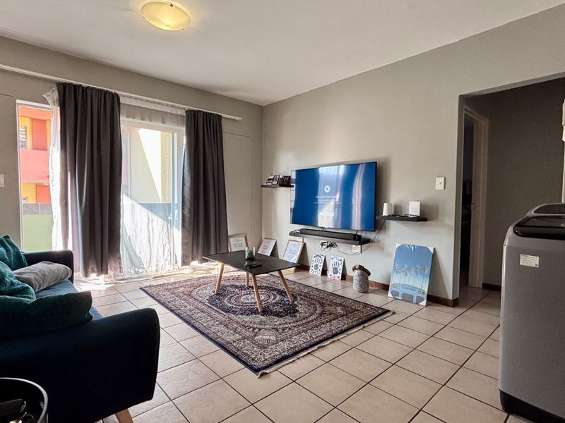 A living room featuring tiled flooring and a sliding glass door providing access to an outdoor area.